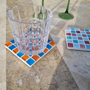 Aperol coaster, bright multicoloured glass tiles on travertine in the sun