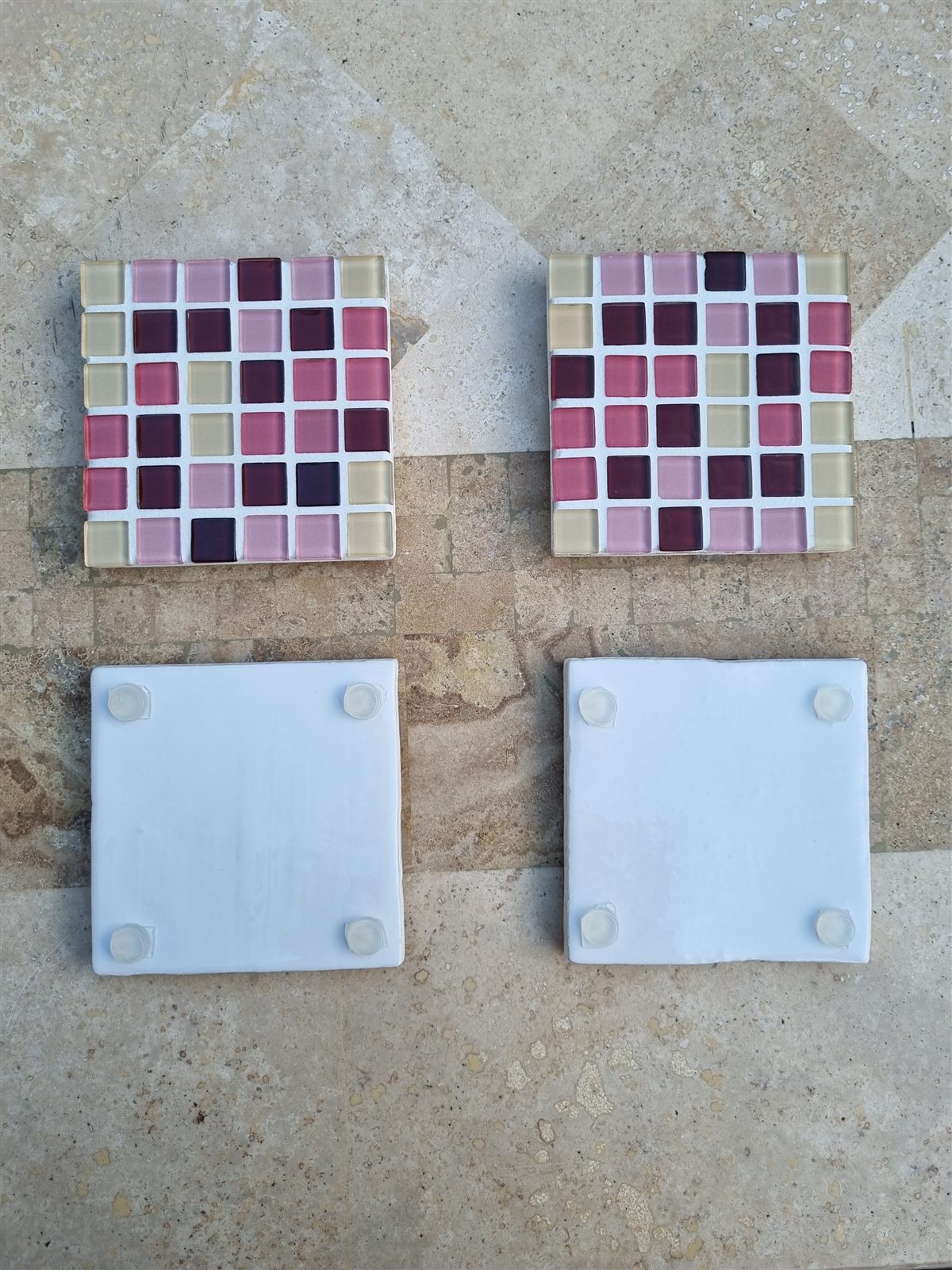 Finished glass coasters beside blank bases with silicone feet, on the studio bench