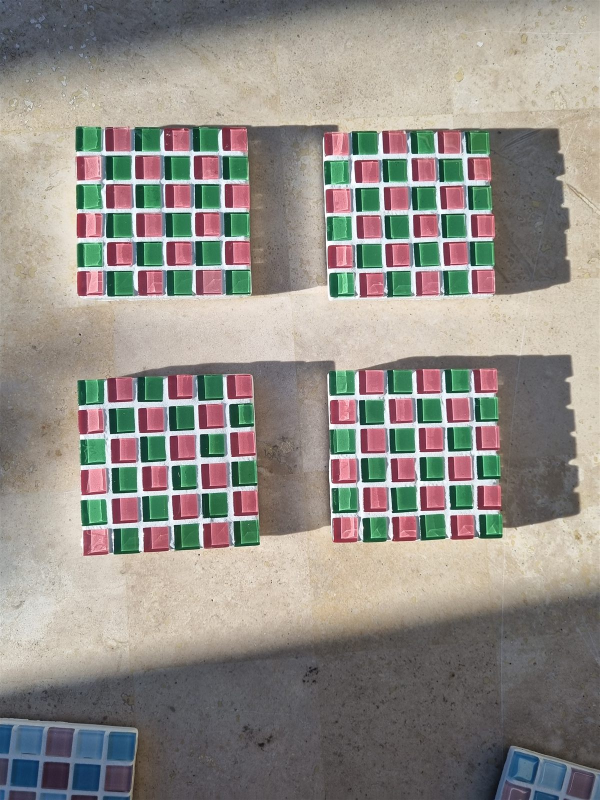 Four Watermelon coasters, pink and green glass tiles, on travertine