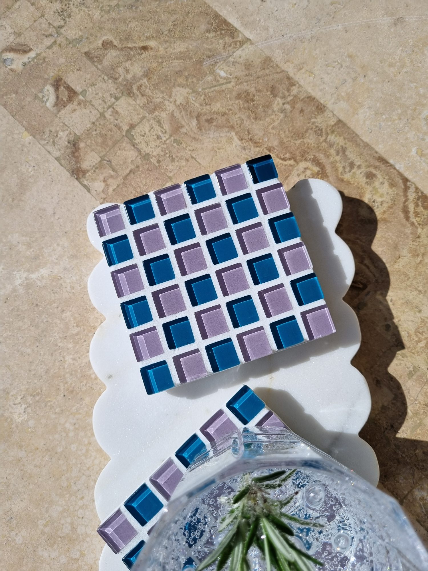 Two Pigeon Wing checkerboard glass coasters on a scalloped marble board